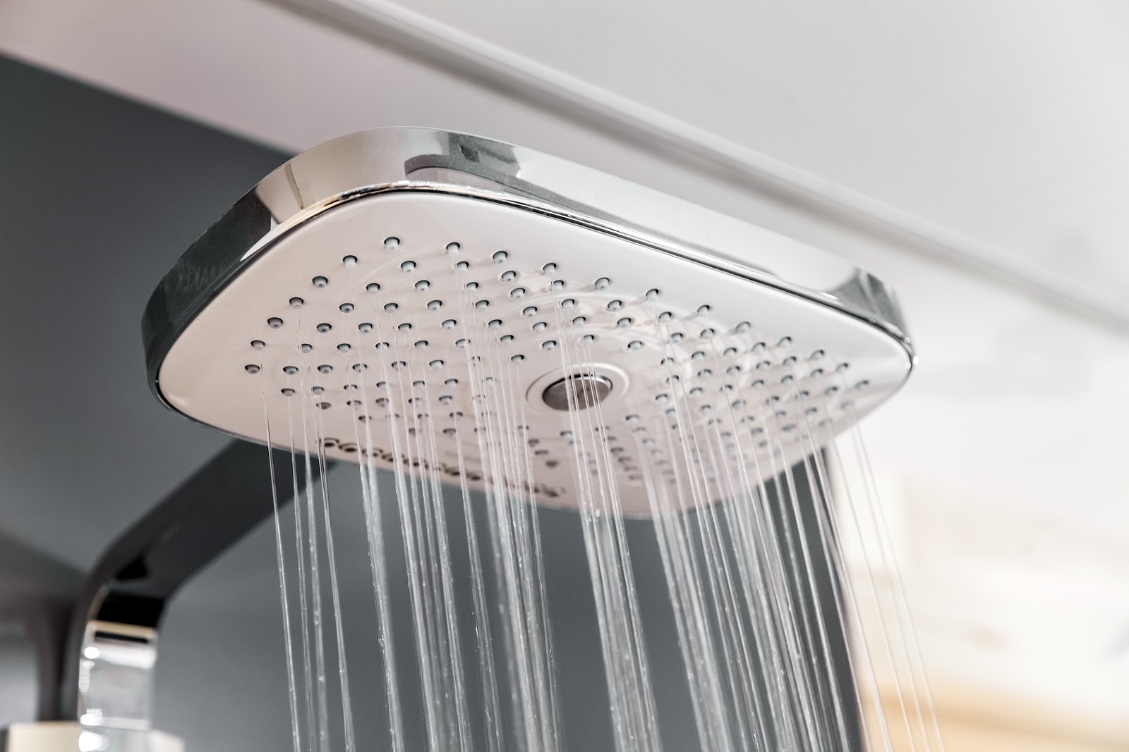 A chrome rainfall showerhead running in a newly fitted shower enclosure.
